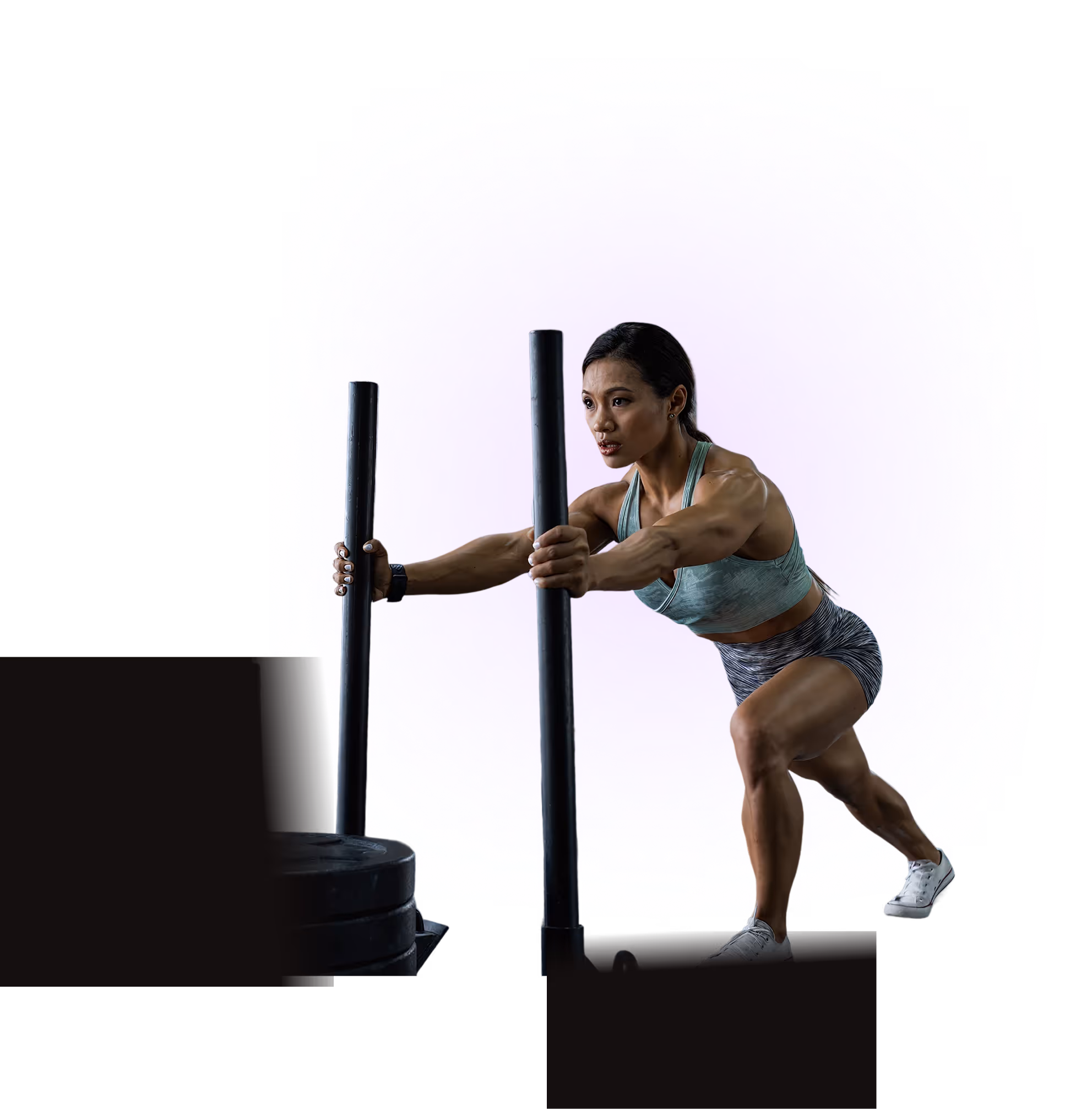 Muscular woman in athletic wear pushing weighted sled forward during strength training.