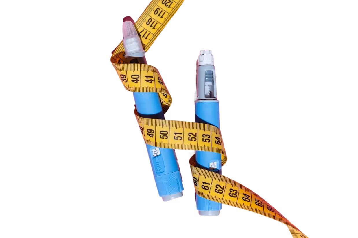 Two blue insulin pens wrapped in a yellow measuring tape on a pink background.